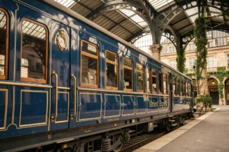Wagon historique de l'Orient Express dans une gare européenne avec architecture en fer forgé et verre